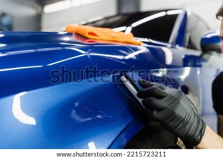 Process of applying ceramic protective coat on body car using sponge in detailing auto service. Car service worker apply ceramic coating to protect the car body from scratches Royalty-Free Stock Photo #2215723211