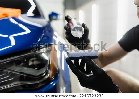 Process of pouring ceramic liquid from bottle on sponge to apply a protective nano layer on car. Detailing service worker applies ceramic protective liquid on sponge close-up Royalty-Free Stock Photo #2215723235