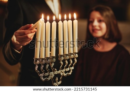 Close up of jewish man lighting silver menorah candle during Hanukkah celebration , copy space