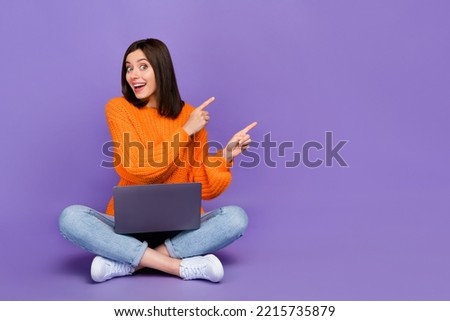 Full length photo of nice young lady point excited empty space laptop wear trendy orange knitwear look isolated on violet color background