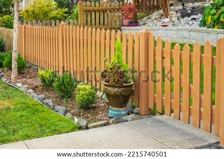 Nice wooden fence around house. Wooden fence with green lawn. Entrance gate. Street photo, nobody, selective focus Royalty-Free Stock Photo #2215740501