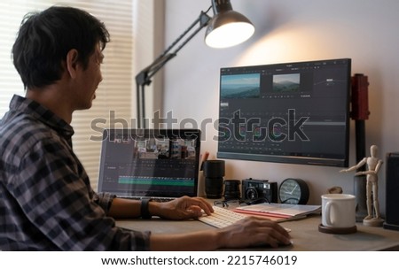 Side view of male videographer working on professional computer with video editing and color correction.