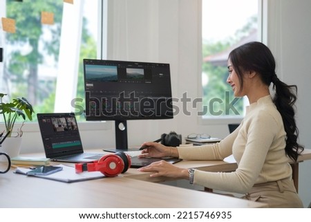 Side view of young female videographer working on professional computer with video editing and color correction.