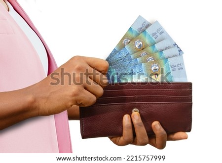 fair Female Hand Holding brown Purse With Kuwaiti dinar notes, hand removing money out of purse isolated on white background Royalty-Free Stock Photo #2215757999