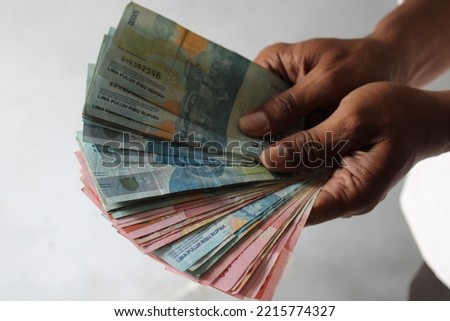 a man's hand holding money on a grey background