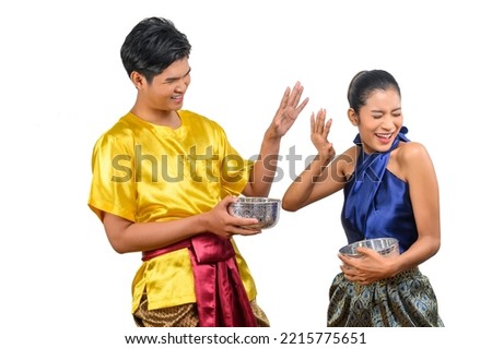 Portrait young couple in Songkran festival with Thai Traditional costume holding water bowls, They are smile and laugh with fun on white background. Thailand culture with Thai's new year day Royalty-Free Stock Photo #2215775651