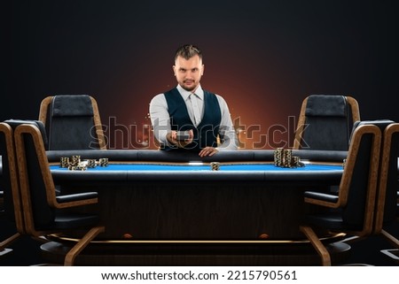 Male croupier at the poker table, poker room. Poker game, casino, Texas hold'em, online game, card games. Modern design, magazine style Royalty-Free Stock Photo #2215790561
