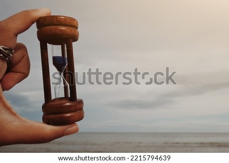 hand holding hourglass, sea and sky copy space background for text, saving and manage time to success business, relaxation and lifestyle, travel and vacation wallpaper concept