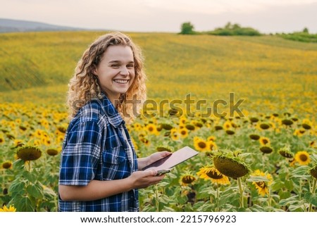 Portrait of an agronomist woman with a tablet in his hands working in field doing the analysis of growth of sunflowers. Summer nature. Agricultural worker