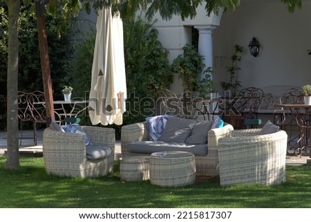 Garden seating area with table, armchairs and a parasol.