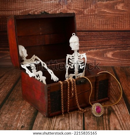 halloween composition with skeletons in a treasure chest and pumpkins as Jack O Lantern on wooden background. Still life	