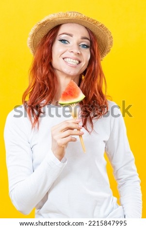 One Winsome Caucasian Pretty Young woman in straw hat holding sliced piece of juicy watermelon on fork against color background.Vertical Composition