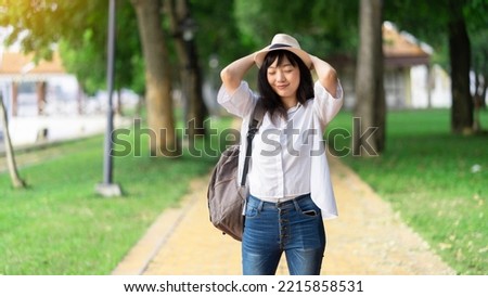 Lifestyle Image of carefree traveling smiling woman in white shirt and  hat spending her leisure time on the park. Summer mood.