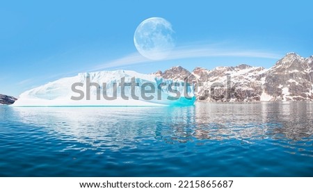 View of Greenland glaciers and iceberg from the village of Kulusuk with full moon - Kulusuk, Greenland - Melting of a iceberg and pouring water into the sea   "Elements of this image furnished by NASA