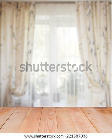 Blurred picture of window with curtains on the wooden surface