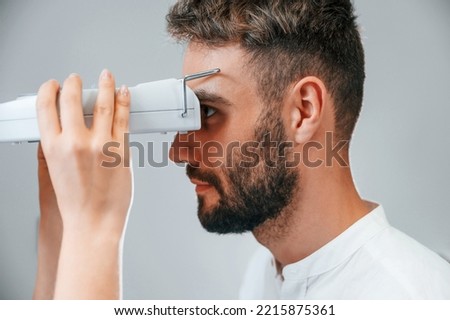 Side view. Man's vision checked by female doctor in the clinic by using special optometrist device.