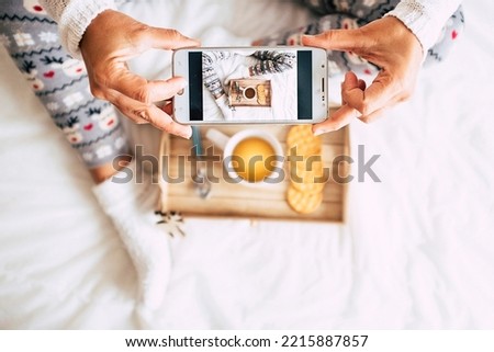 Above view of woman taking food picture of morning breakfast sitting on bed. White copy space of people having photo of coffee and cakes. Christmas holiday leisure activity at home female waking up