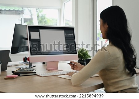 Rear view of female photo editors sitting in creative workplace and retouching photos on personal computer
