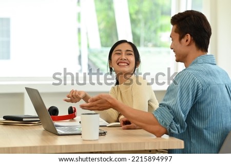 Cheerful young woman discussing online information, sharing idea for new startup project with her colleague in office