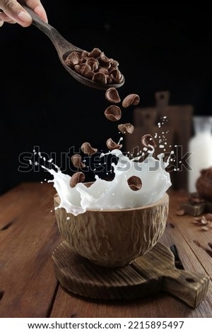 splash milk, a cereal poured into a wooden bowl filled with milk
