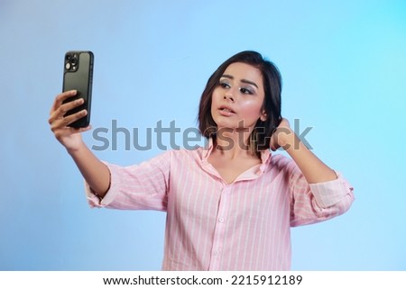 Image of beautiful Hispanic girl taking her selfie or talking on a video call  isolated over gradient blue background
