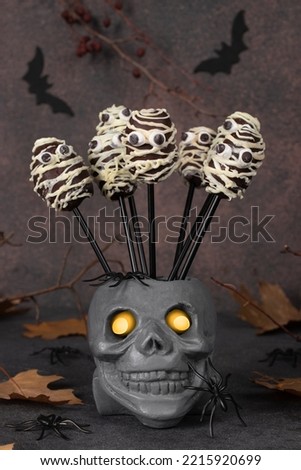 Chocolate Cake Pops Shaped Mummy and skull with glowing eyes on brown background