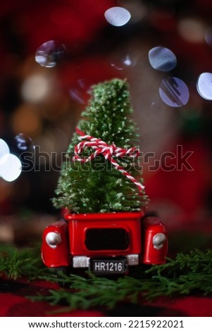 Christmas decoration. Unfocussed back of little red truck with christmas tree inside. Blurred background.