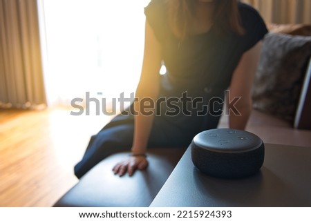 Woman sitting on a chair and talking to a voice recognition device with sunlight background Royalty-Free Stock Photo #2215924393