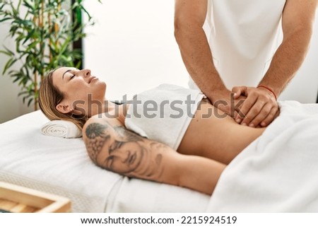 Young caucasian woman at physiotherapy clinic getting muscle massage by professional therapist. Physiotherapist man doing stomach pain treatment to client