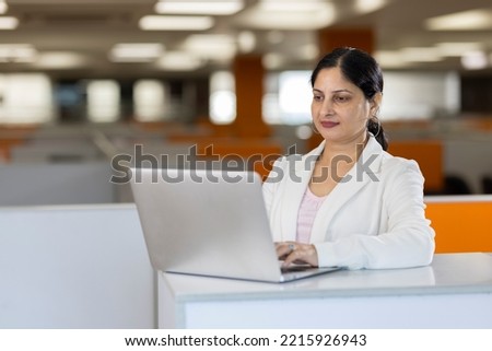 Happy businesswoman using laptop in office.