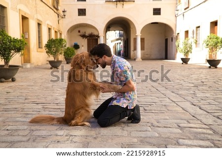 young latino man and his brown golden retriever dog kneeling on the ground while looking at each other with their heads together in sign of affection and love. Concept pets, animals, dogs, pet love.