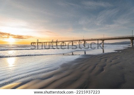Beautiful sunrise at New Brighton Pier, Christchurch, New Zealand. It is one of eastern country's main entertainment and tourist centers, with its architecturally unique pier and scenic coastline. Royalty-Free Stock Photo #2215937223