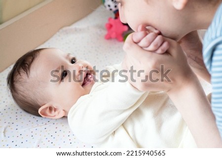 Young mother, kissing her baby boy at home. Family concept. Closeup portrait of loving mother young woman kissing little kid, home interior.