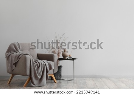 Interior of modern living room with soft armchair, table and tree branches Royalty-Free Stock Photo #2215949141