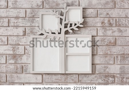 Family tree with photo frames hanging on light brick wall