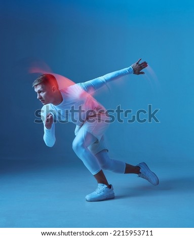 Sprinter start. Male strong muscular athlete starts running on blue background.