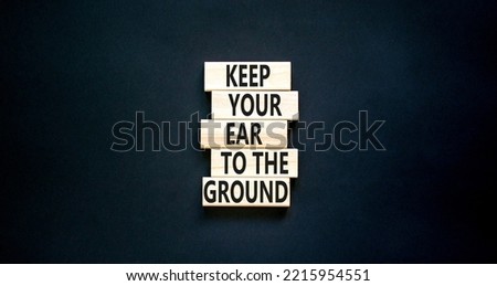 Keep your ear to the ground symbol. Concept words Keep your ear on the ground on wooden blocks. Beautiful black table black background. Business keep your ear on the ground concept. Copy space.