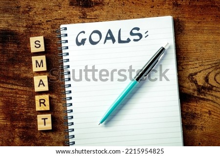 Smart Goals concept. A notepad with the handwritten word, for writing a plan or a list, overhead flat lay shot on a wooden desk Royalty-Free Stock Photo #2215954825