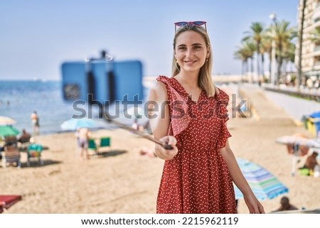 Young blonde girl smiling happy making selfie by the smartphone at the beach