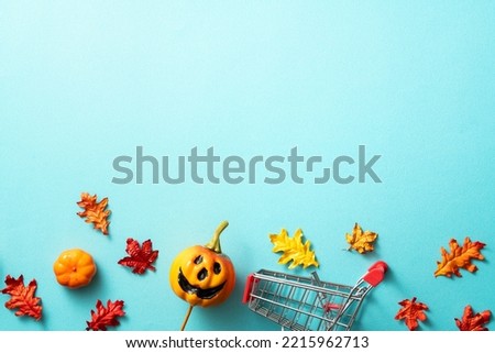 Creative Halloween autumn shopping design concept decoration on blue paper table background with pumpkin, autumn leaves and copy space