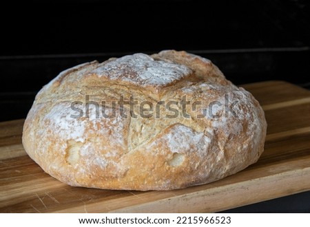 Stonebaked artisan 'White Boule' bread on cutting board  Royalty-Free Stock Photo #2215966523