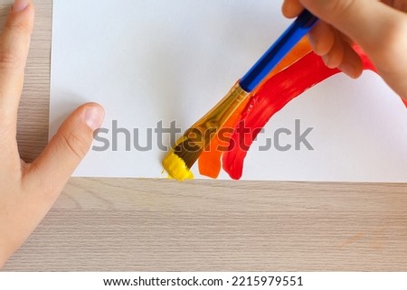 child's hand draws a rainbow on a white background