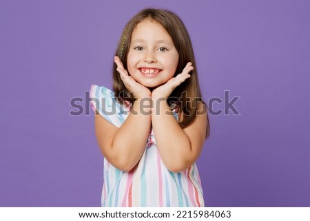 Little smiling nice cheerful happy european fun kid child girl 6-7 years old wears striped dress hold face isolated on plain pastel light purple background. Mother's Day love family lifestyle concept Royalty-Free Stock Photo #2215984063