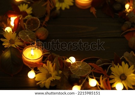 dark rustic wooden background with candles, autumn leaves and copy space