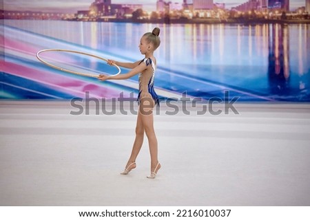 girl gymnast performs an exercise with a hoop