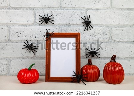 Photo frame mockup with autumn decorations and pumpkins on brick wall background. Thanksgiving, Halloween holiday poster design. Spiders on the wall.