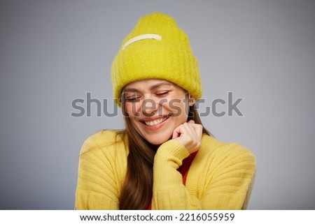 Happy smiling woman with closed eyes wearing winter yellow hat. Advertising female studio portrait.