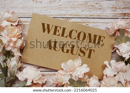 Welcome August typography text with flowers frame on wooden background
