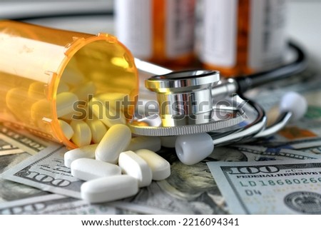 Stethoscope laying on medicine white pills  money with RX prescription drug bottle HSA FSA costs Royalty-Free Stock Photo #2216094341
