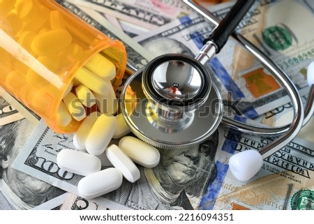 Stethoscope laying on medicine  pills money - concept medical expenses, prescription drugs costs Royalty-Free Stock Photo #2216094351